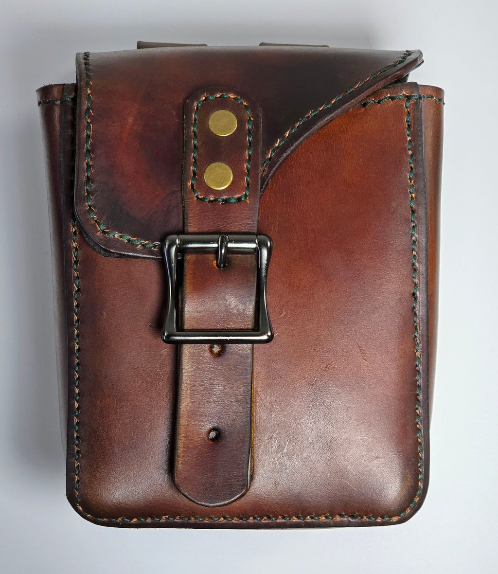 Brown leather pouch with a buckle on a light gray background