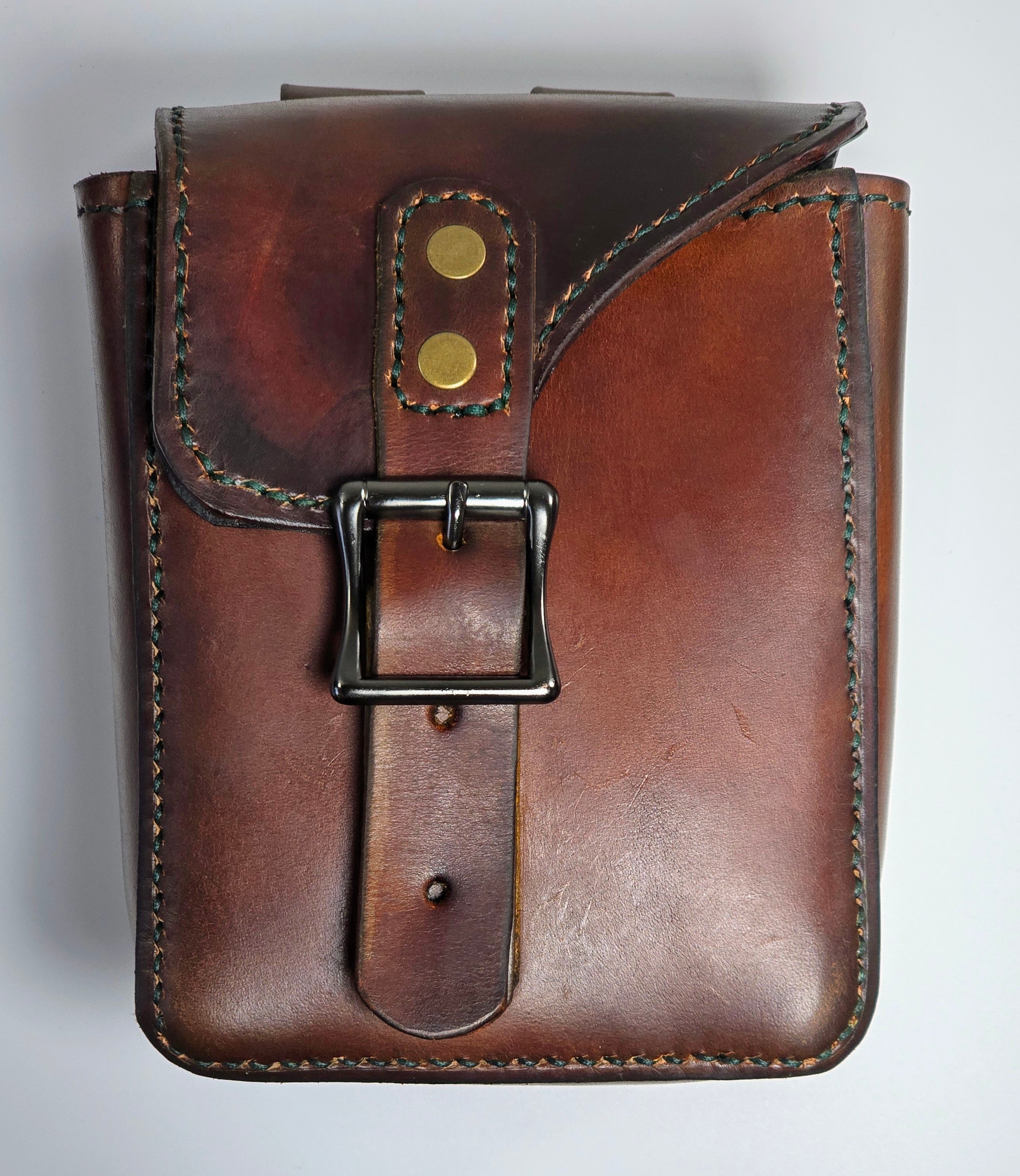 Brown leather pouch with a buckle on a light gray background