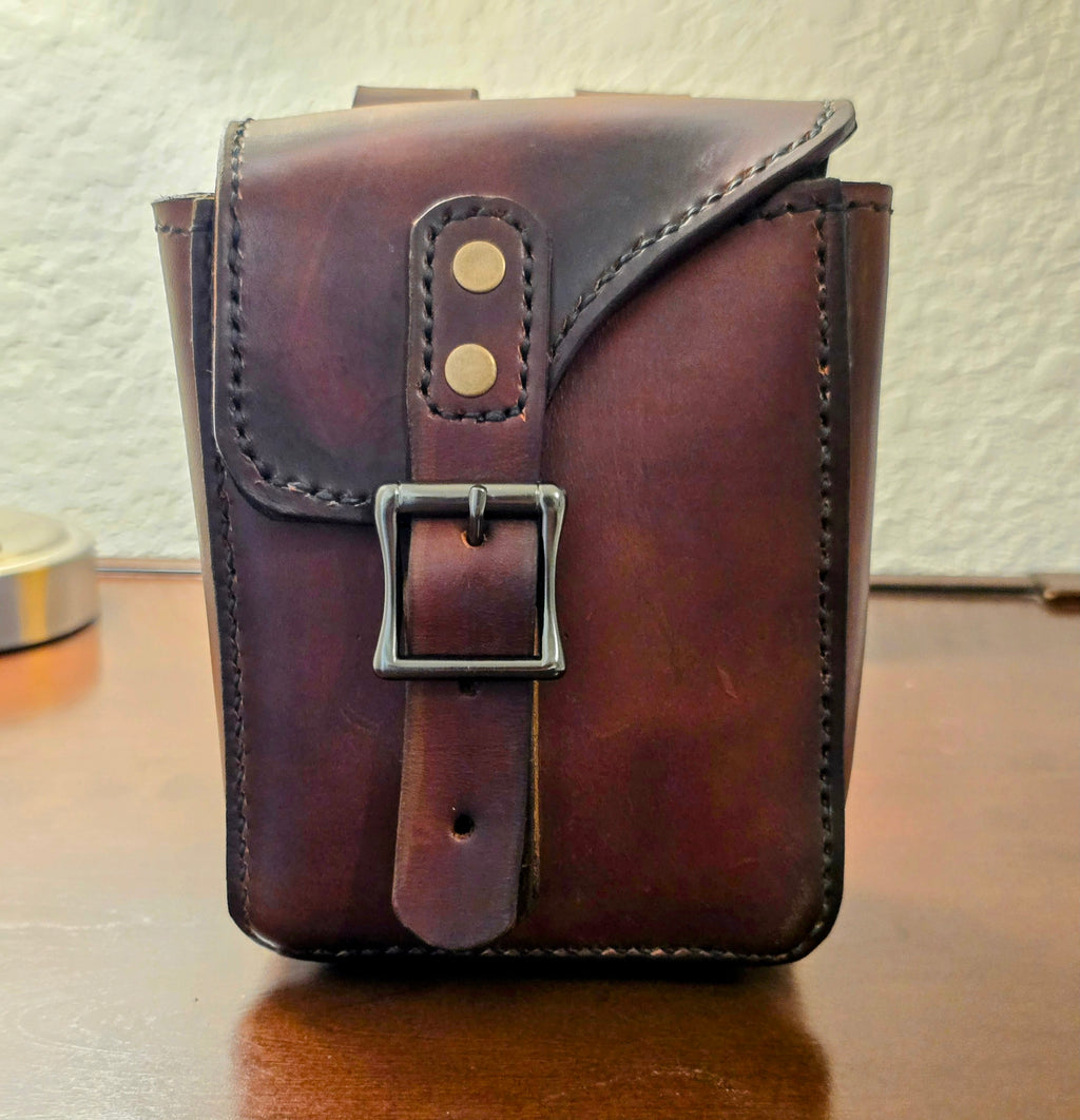 Brown leather pouch with a buckle on a wooden surface