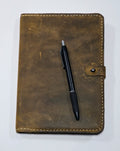 Brown leather journal cover with a pen on a white background