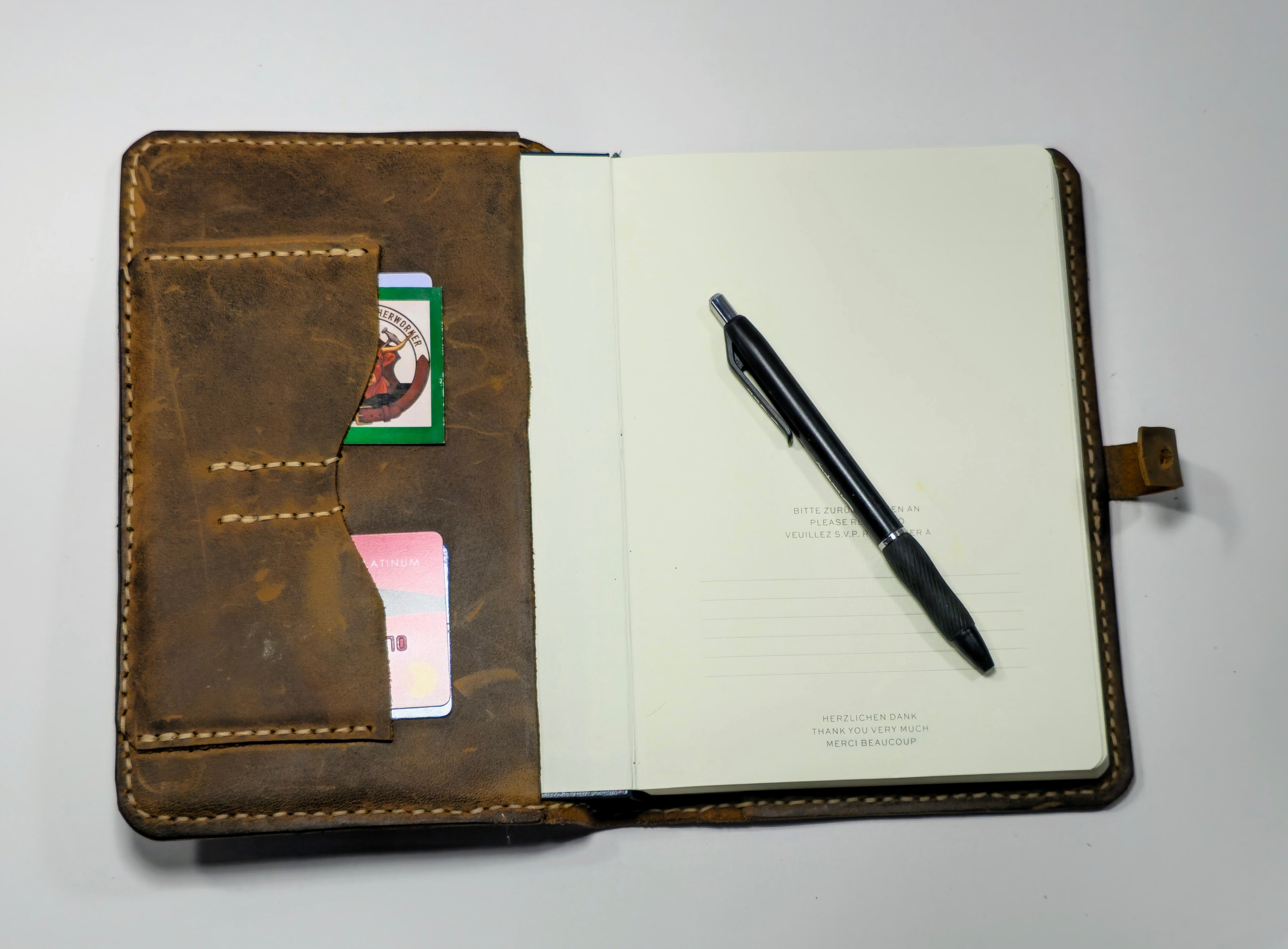 Brown leather journal cover with pen, journal and cards on a white background