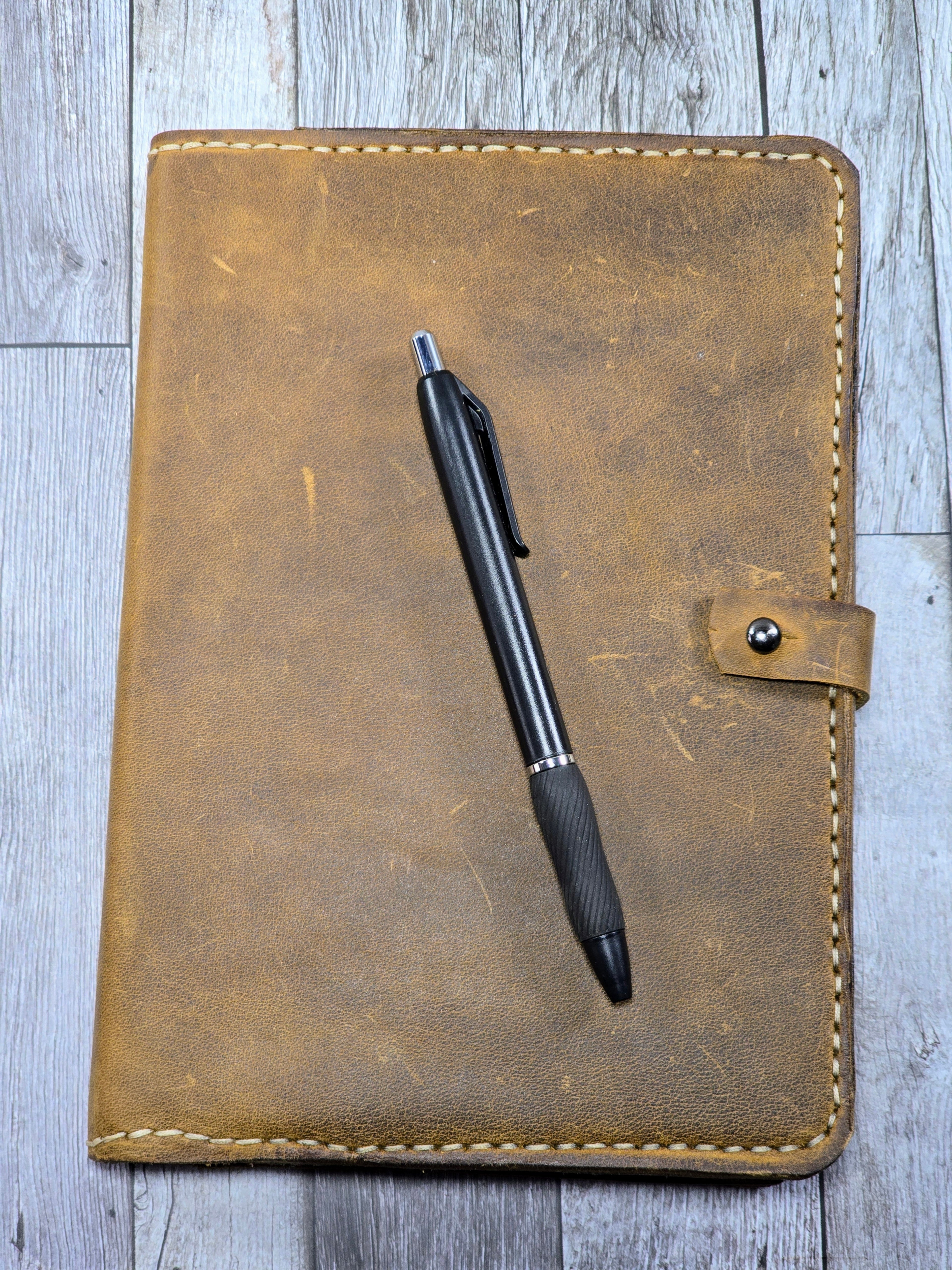 Brown leather notebook with a pen on a wooden surface