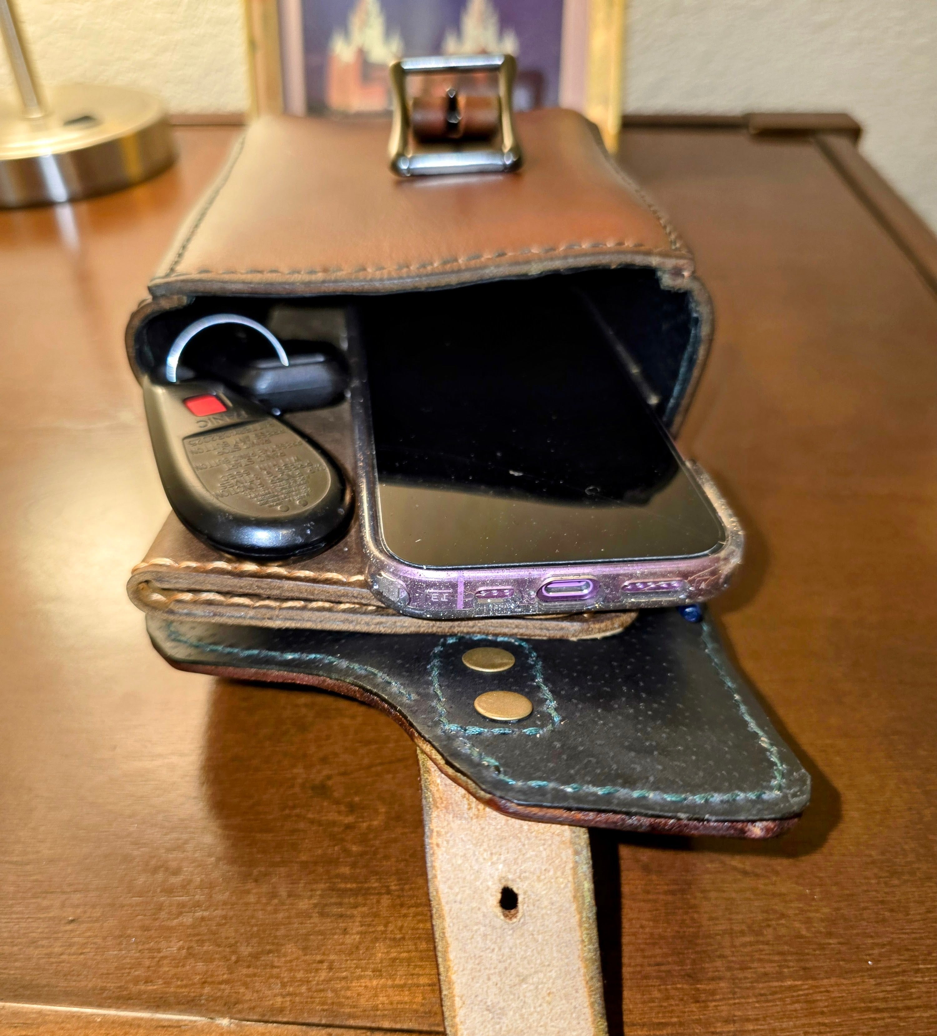 Leather wallet with phone and car keys on a wooden surface