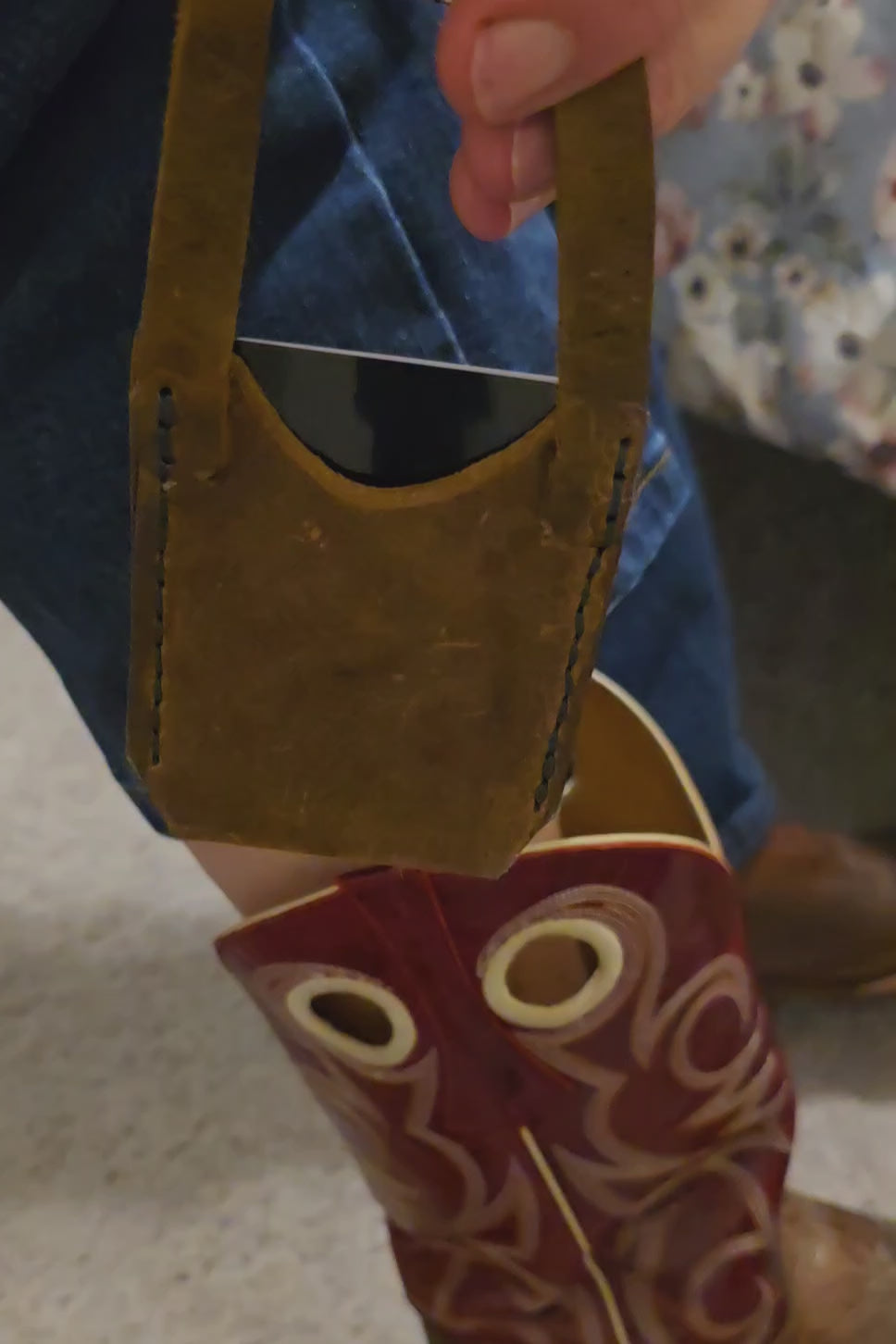 A 30-second instructional video showing the user unboxing and attaching the "Spur Sleeve." The video demonstrates: unfastening the snap-handle of the rustic brown leather sleeve, carefully looping the strap through the pull hole of a decorative red cowboy boot, and securing the polished metal snap. It highlights the full range of motion while walking and the ease of accessing the single card kept securely and comfortably.
