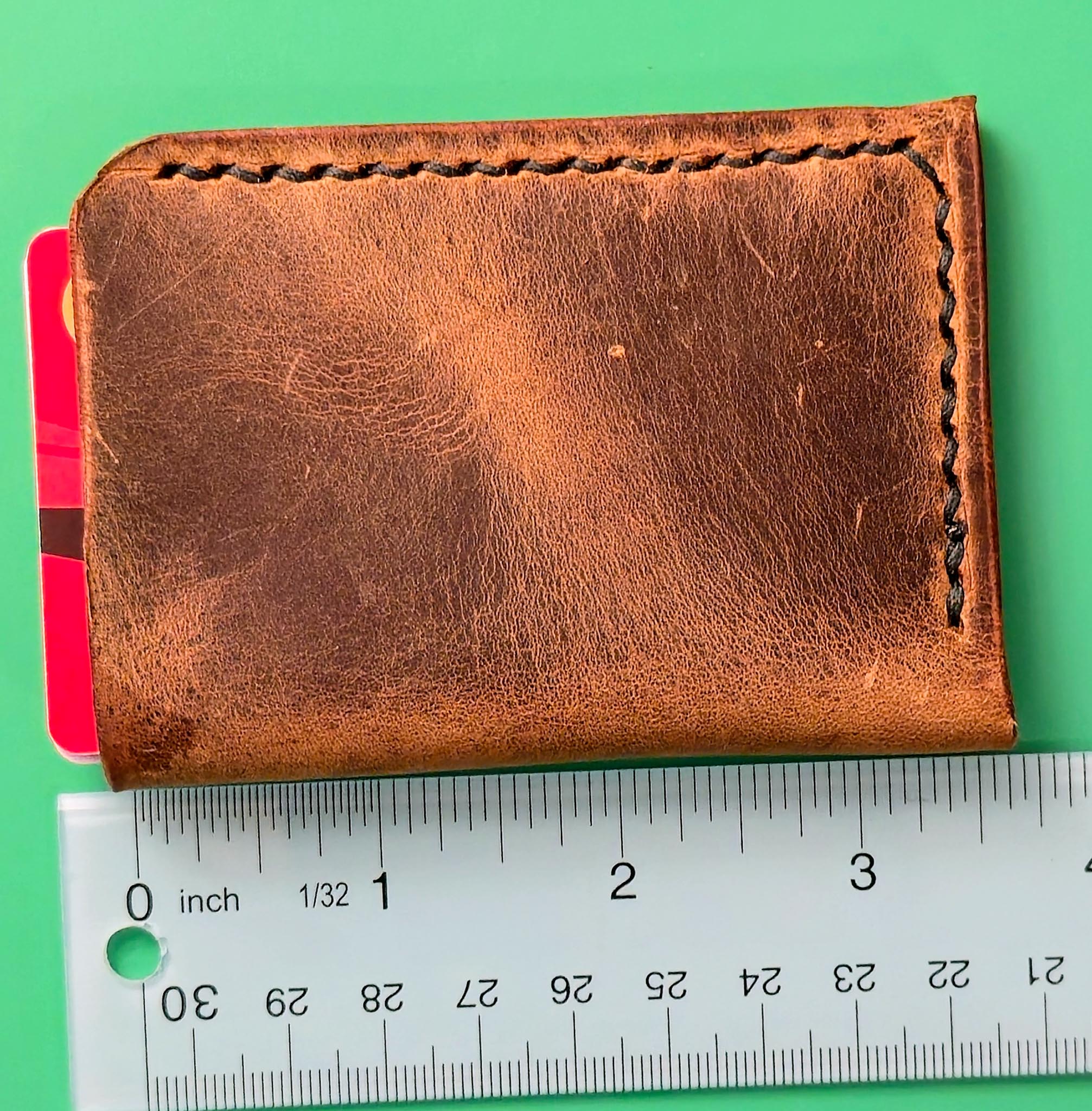 Brown leather wallet with a ruler for scale on a green background