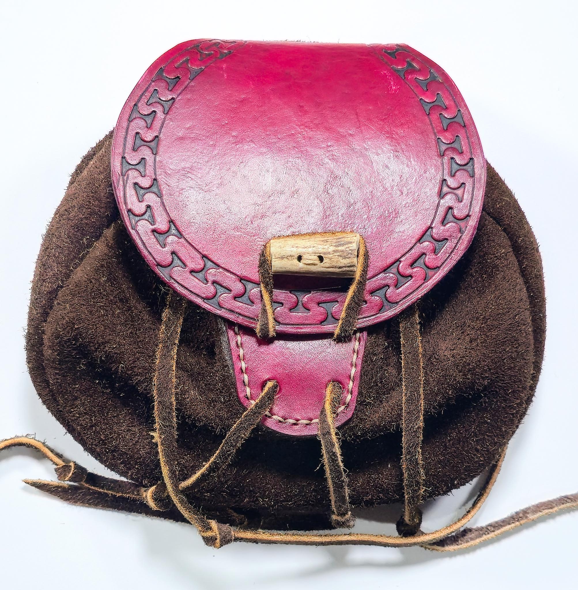 Hand-tooled bison leather belt pouch with a handmade leather closure and intricate geometric patterns.