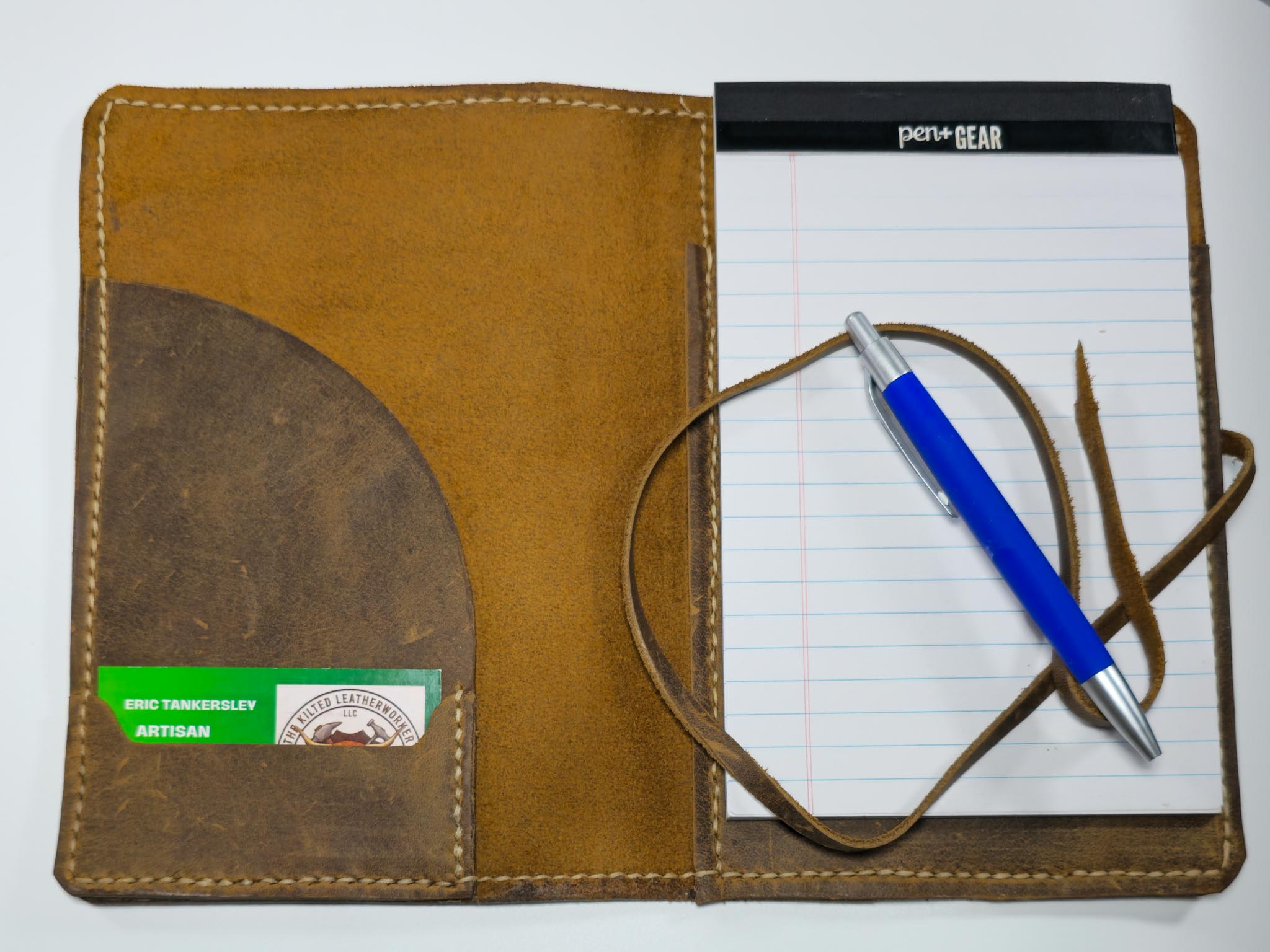 Brown leather mini padfolio with a pen and notepad on a white background