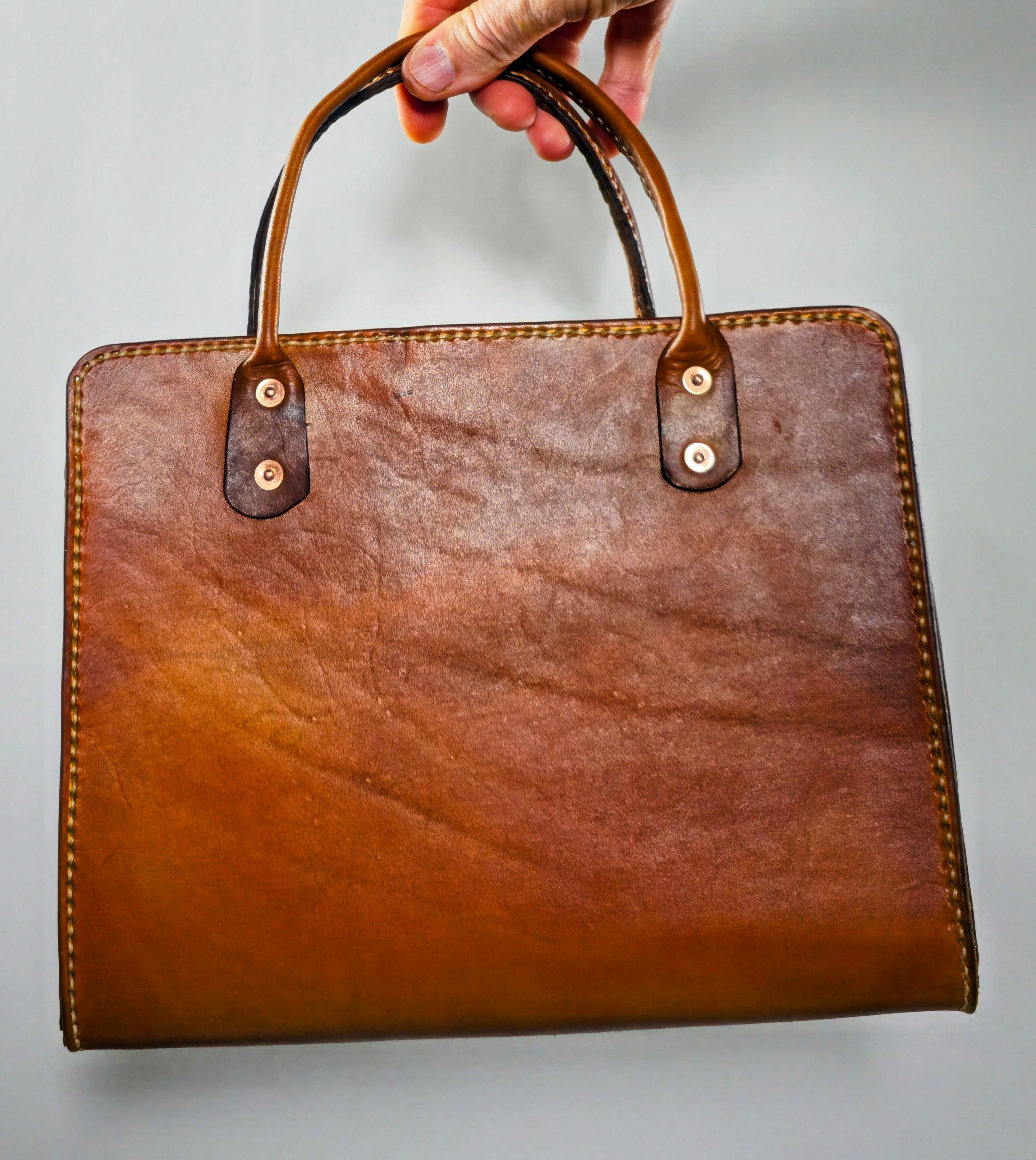 Hand-stitched vintage style leather book tote in rich brown veg tan leather showing durable handles and clean stitching