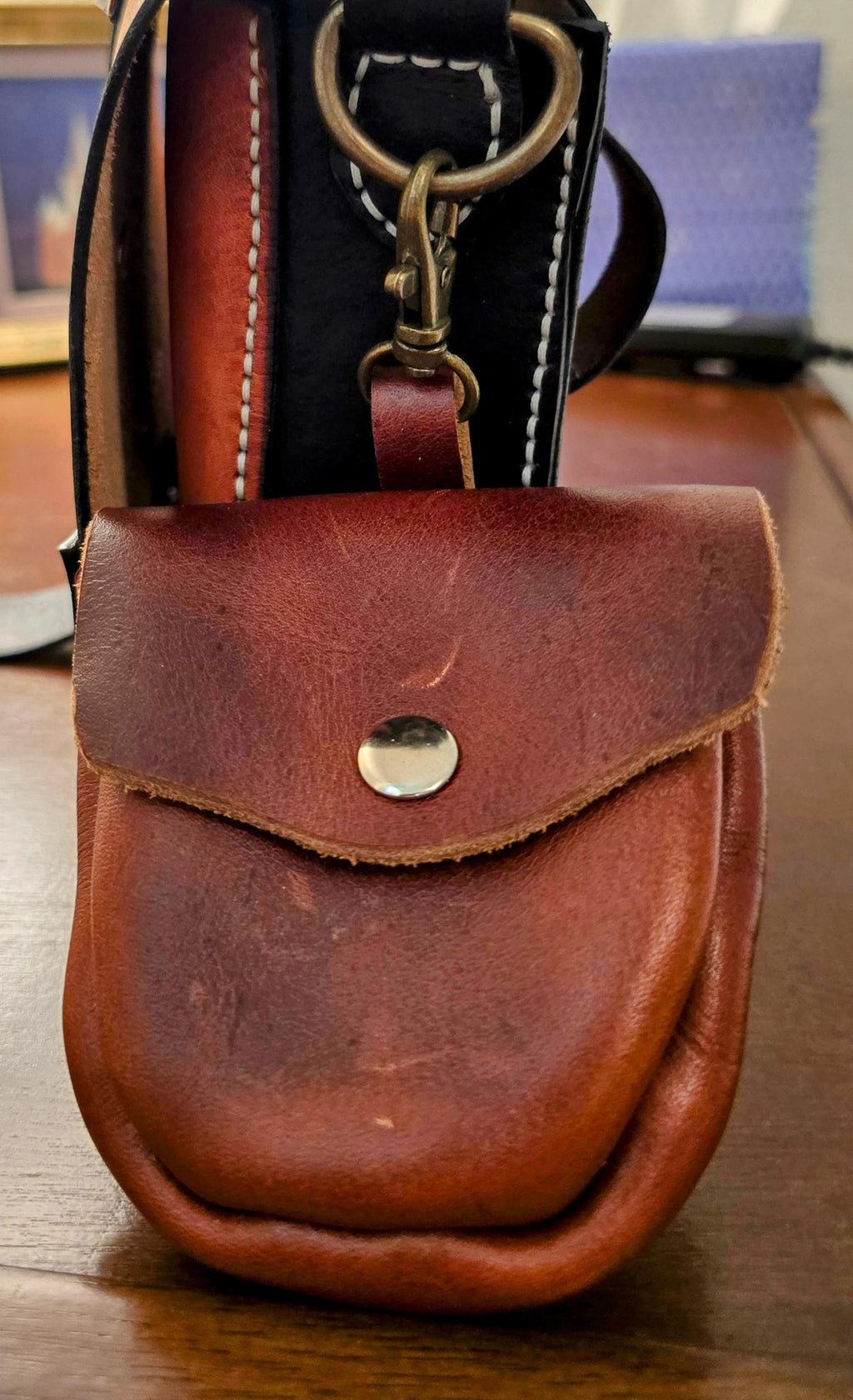 Brown leather pouch with a metal clasp on a wooden surface