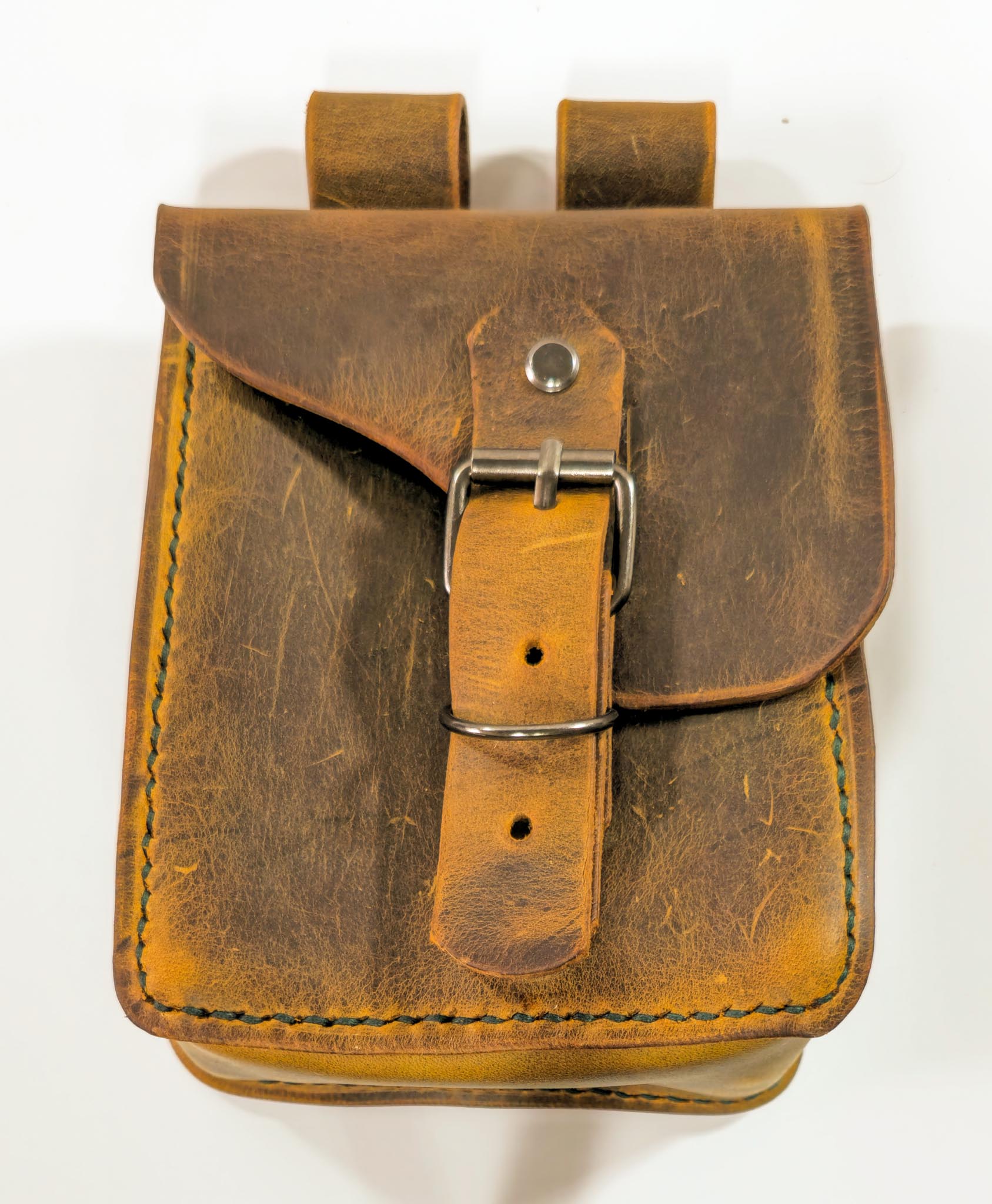 Handcrafted brown leather belt pouch with buckle closure on white background