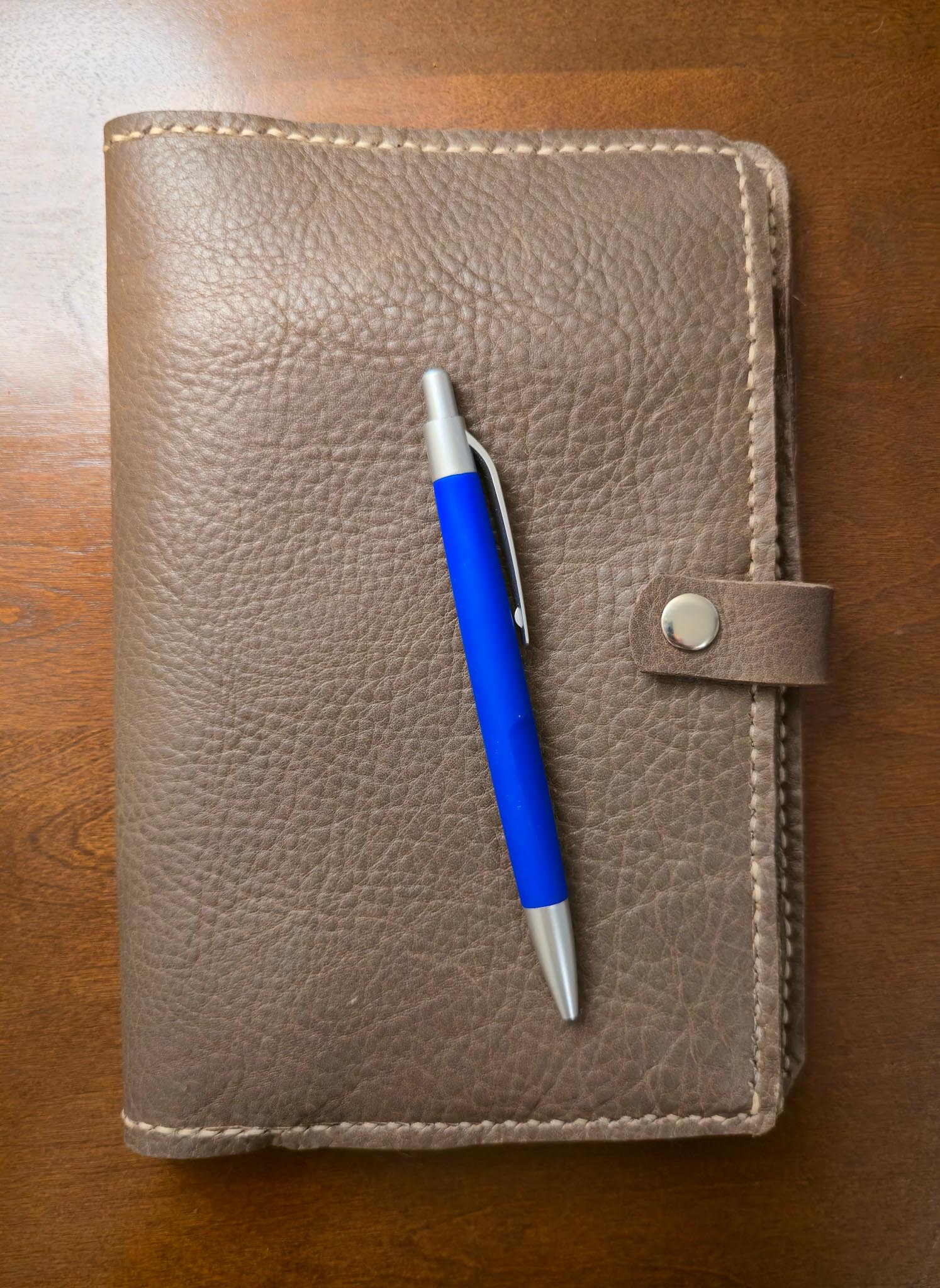 Brown leather notebook with a blue pen on a wooden surface