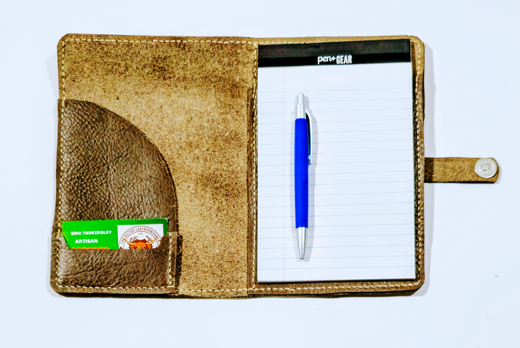 Open view of Brown leather mini padfolio with a blue pen on a white background