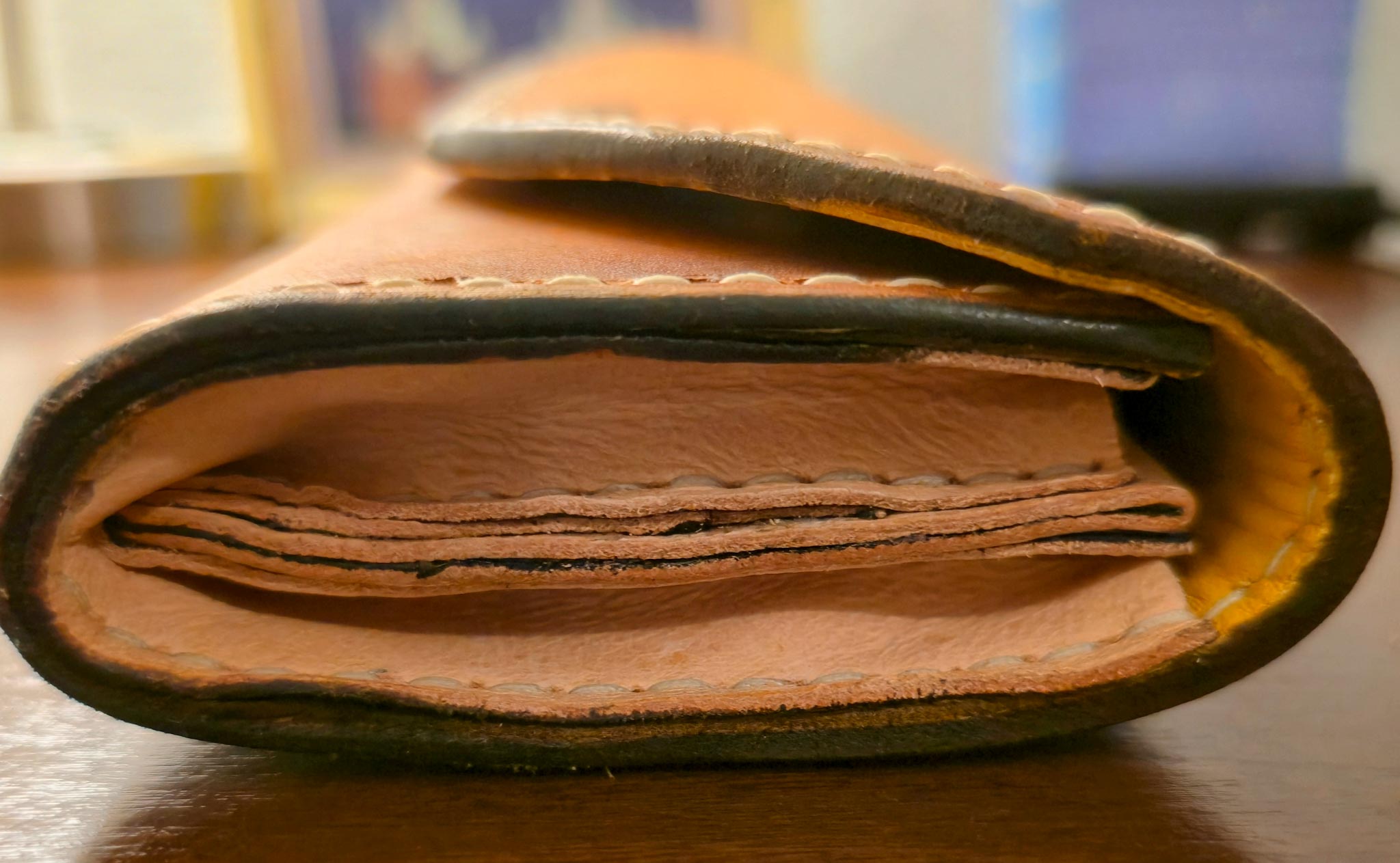 Close up of side view of clutch wallet on brown table.