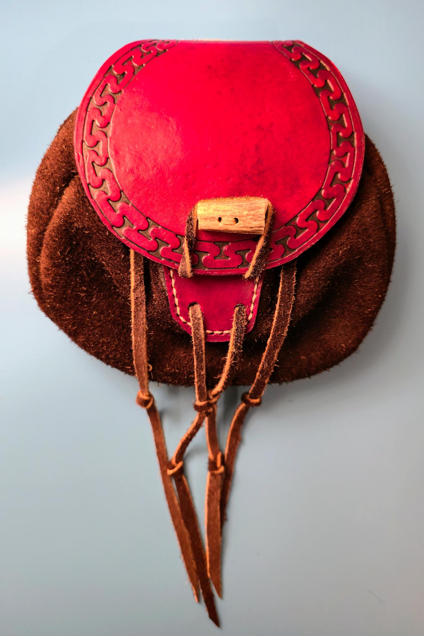 Hand-tooled bison leather belt pouch with a deer antler closure and intricate geometric patterns.