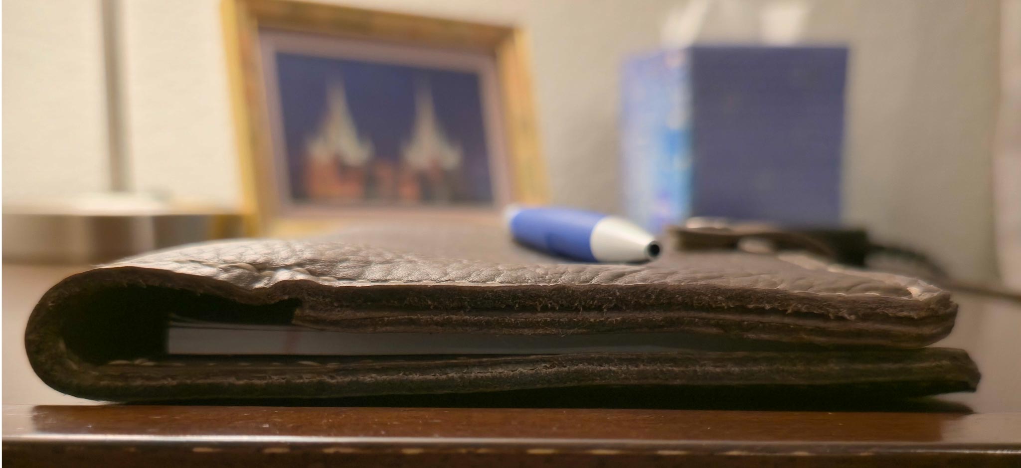 Brown leather wallet on a wooden surface with a blurred background