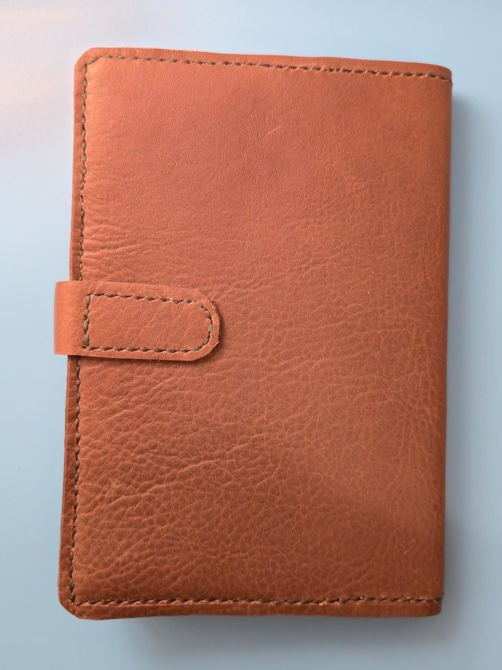Back of Brown embossed leather journal cover on a light blue background