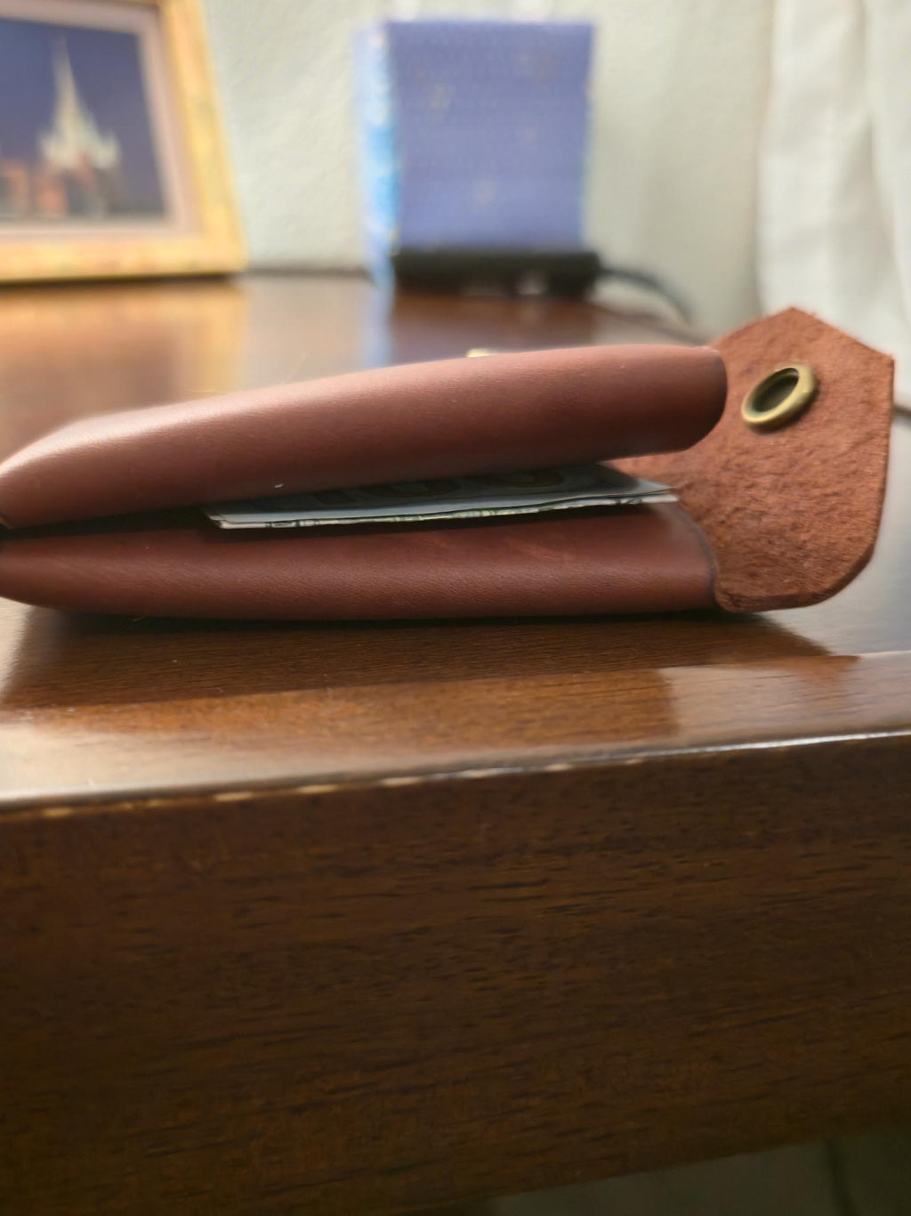 Burgundy leather wallet with an antique brass snap accents on a wooden surface