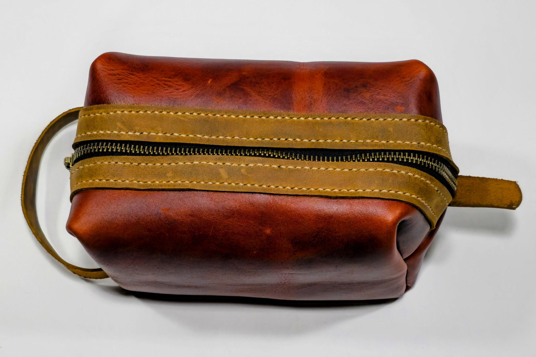 Burgundy leather toiletry bag with brown zipper on a white background
