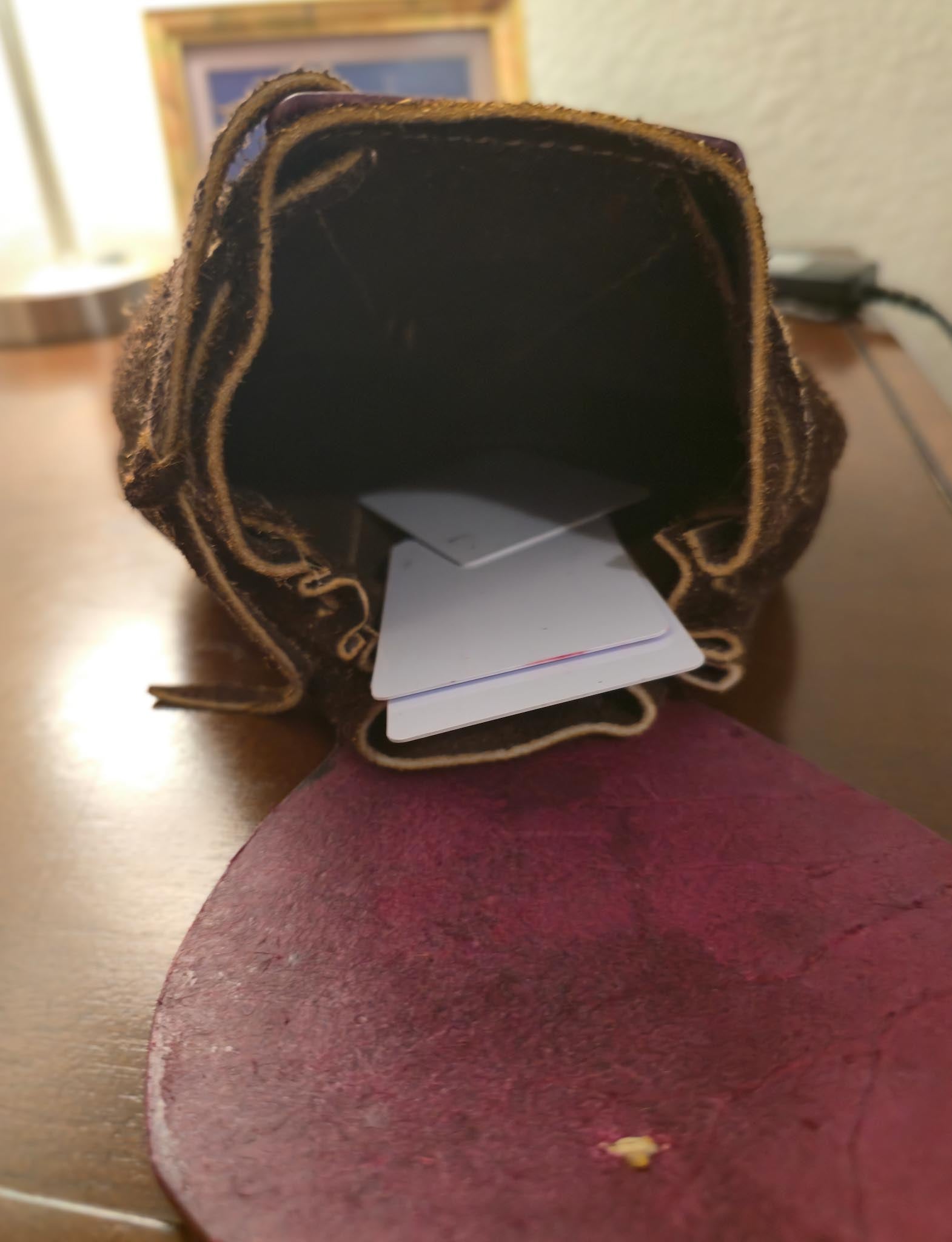 Brown leather pouch with a card inside on a wooden surface