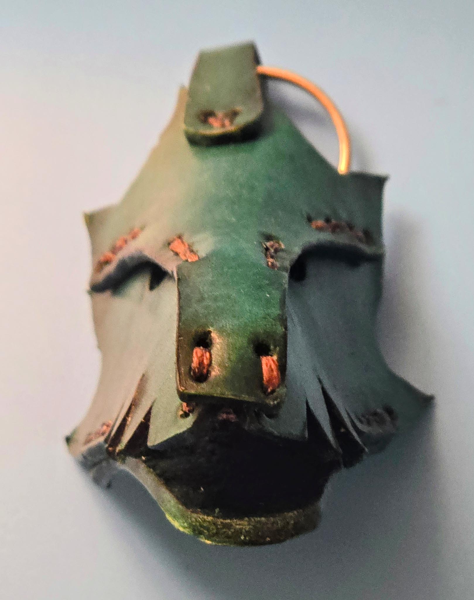 Close-up of a handmade leather dragon key fob showing intricate scale texture and rustic green finish.