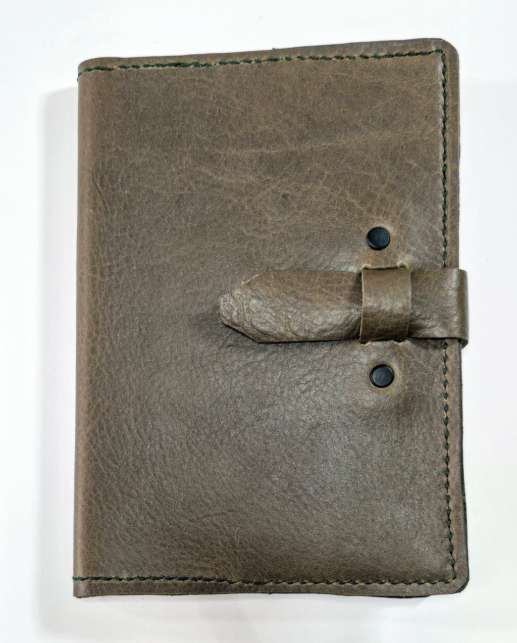 Brown embossed leather journal cover  with a strap closure on a white background