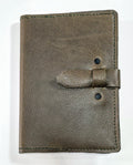 Brown embossed leather journal cover  with a strap closure on a white background