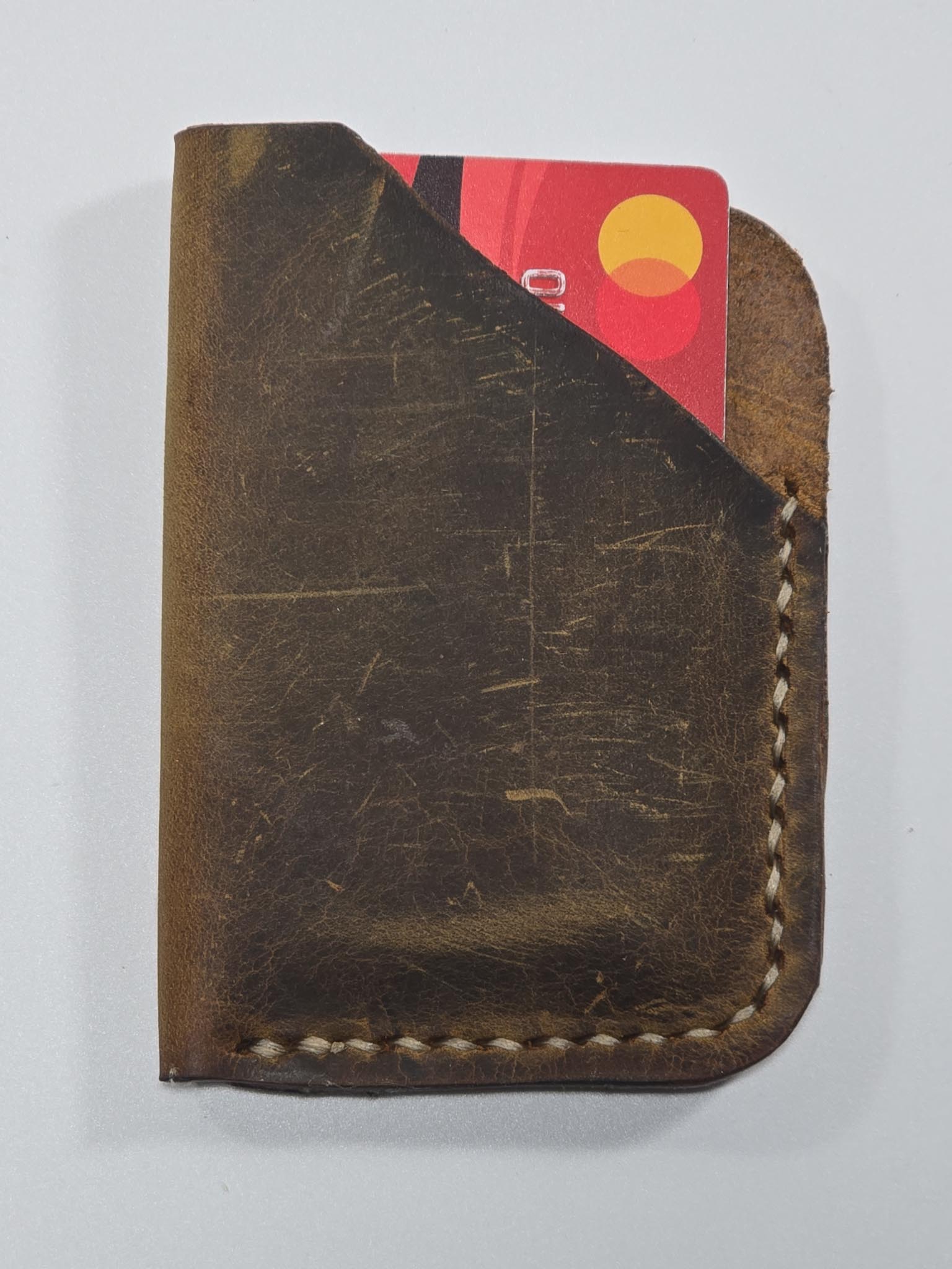 Brown leather wallet with a card peeking out on a white background