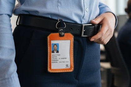 Person wearing brown and black leather ID holder with a white card.
