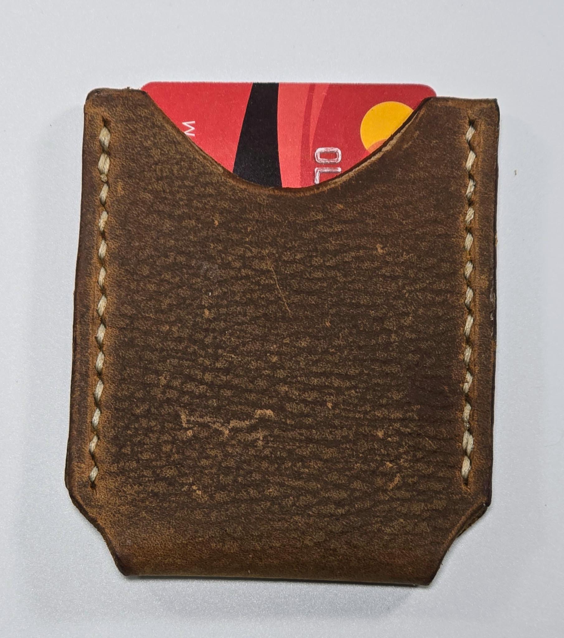 Brown leather cardholder with a red card inside on a white background