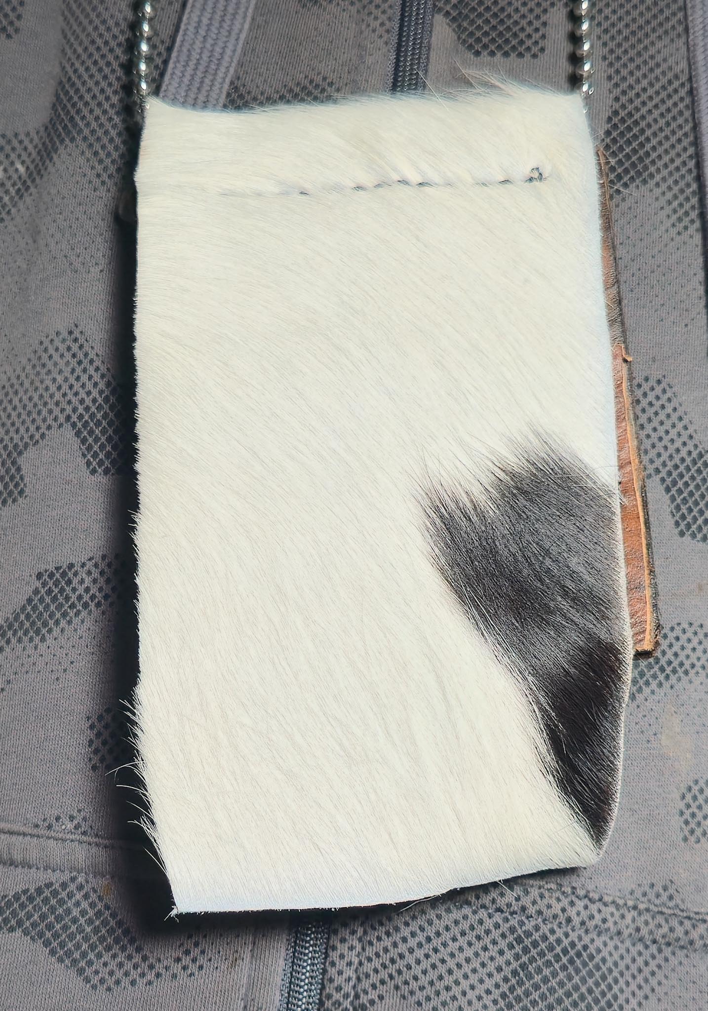 White patch with black hair on a textured gray background